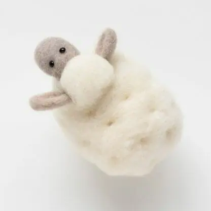 A kit to create a needle felted white sheep.
