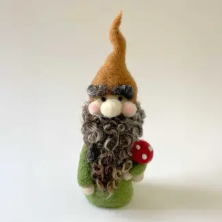 Needle felted gnome with orange pointed hat, gray curly beard, green coat, and red spotted mushroom
